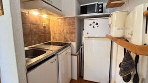 A compact kitchen with a stove, sink, microwave, and refrigerator. - Apartment with lake view - 4 guests (Six-Fours-les-Plages)