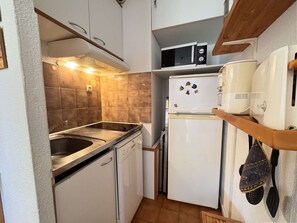 Une cuisine de taille réduite équipée d’une cuisinière, d’un évier, d’un four à micro-ondes et d’un réfrigérateur.