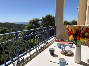 A balcony with a view of the sea, a vase of tulips, and a table with cups and a book. - Studio cabin, AC, sea view - 4 guests (Les Issambres)