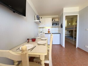 Une cuisine compacte comprenant une table à manger, des chaises, un four à micro-ondes et un four encastré.