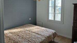 Ein Schlafzimmer mit Bett, Fenster und einer Pendelleuchte.