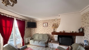 Ein Wohnzimmer mit Kamin, Fernseher und einem Wandteppich mit Muster.