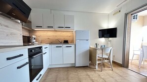 Eine kompakte Küche mit weißen Schränken, einem eingebauten Backofen, einer Mikrowelle und einem Kühlschrank.