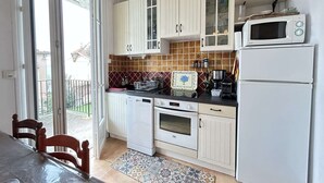 Et køkken med hvide skabe, en mikrobølgeovn, ovn og et spisebord med stole.