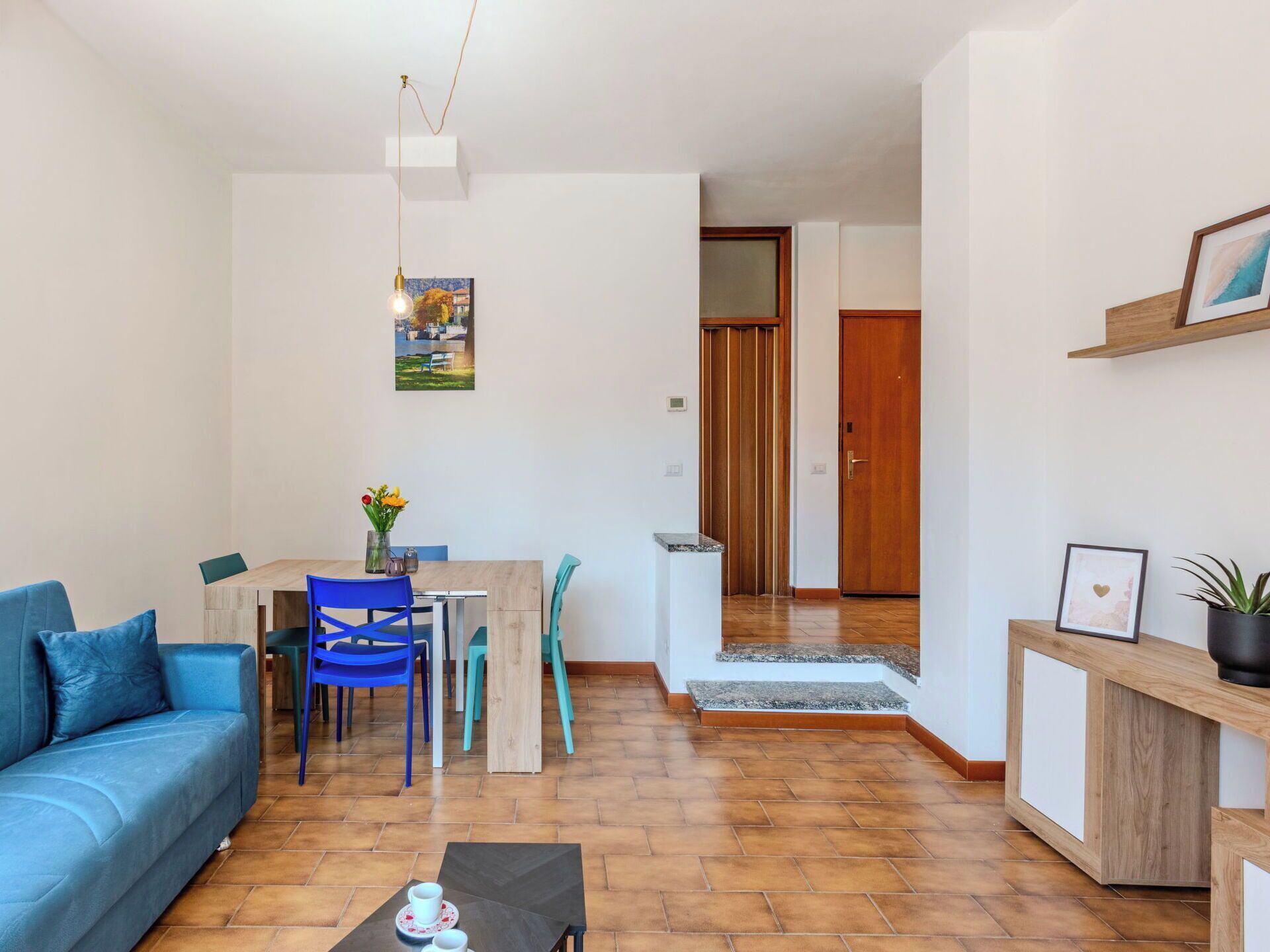 Un espace de vie compact comprenant un canapé, une table à manger, des chaises, une table basse, un meuble en bois et une porte donnant sur une autre pièce.