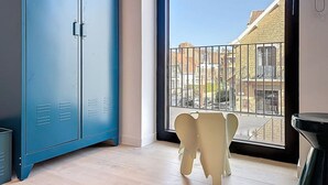 A room with a large window, a blue metal wardrobe, and a white chair. - Flat Seadune - De Panne (De Panne)