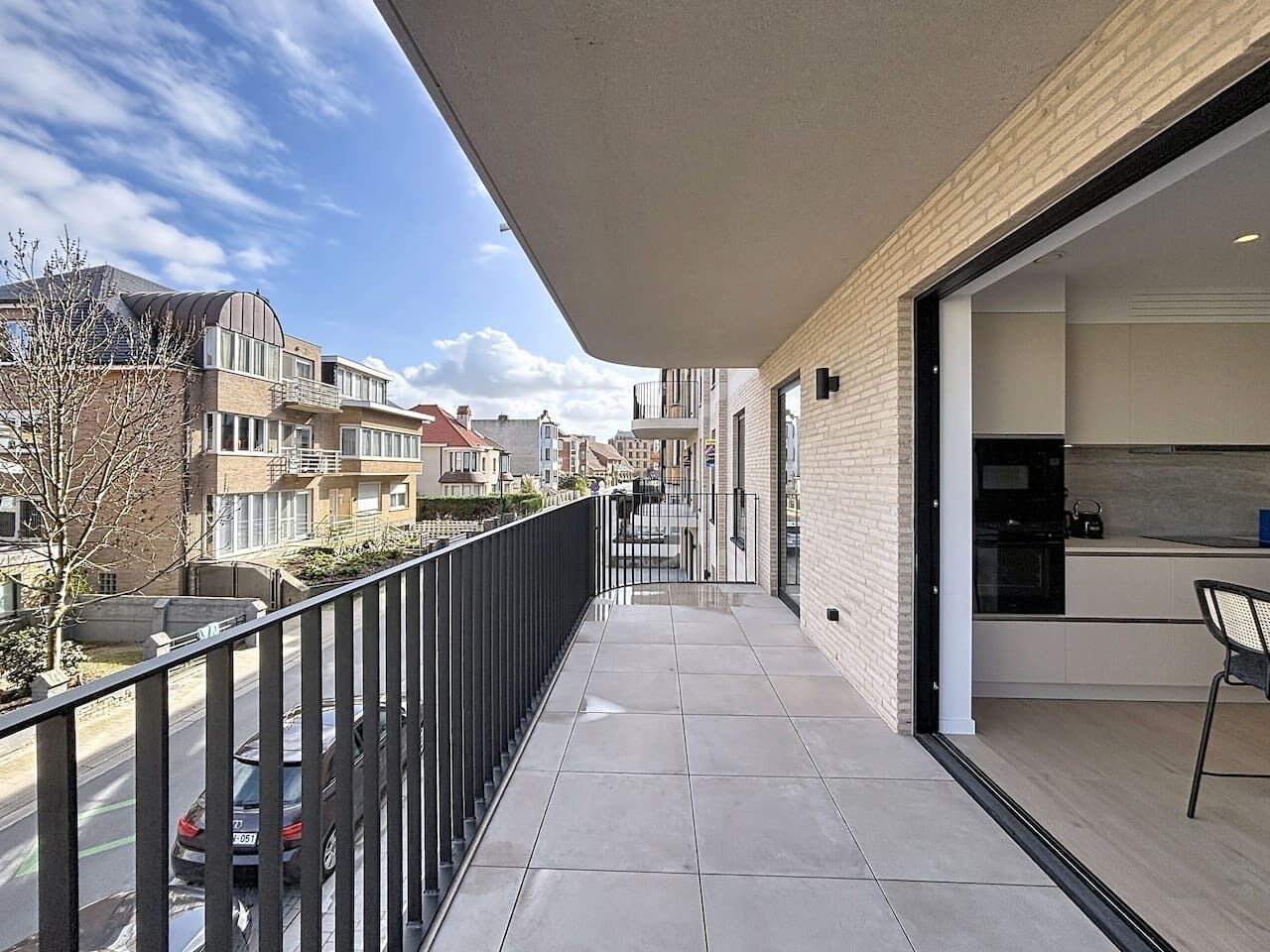 Een balkon met uitzicht op de straat, een moderne keuken en een hekwerk.
