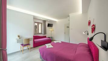 Un dormitorio moderno con una cama grande, un escritorio, una silla, un sofá, un televisor y una lámpara.