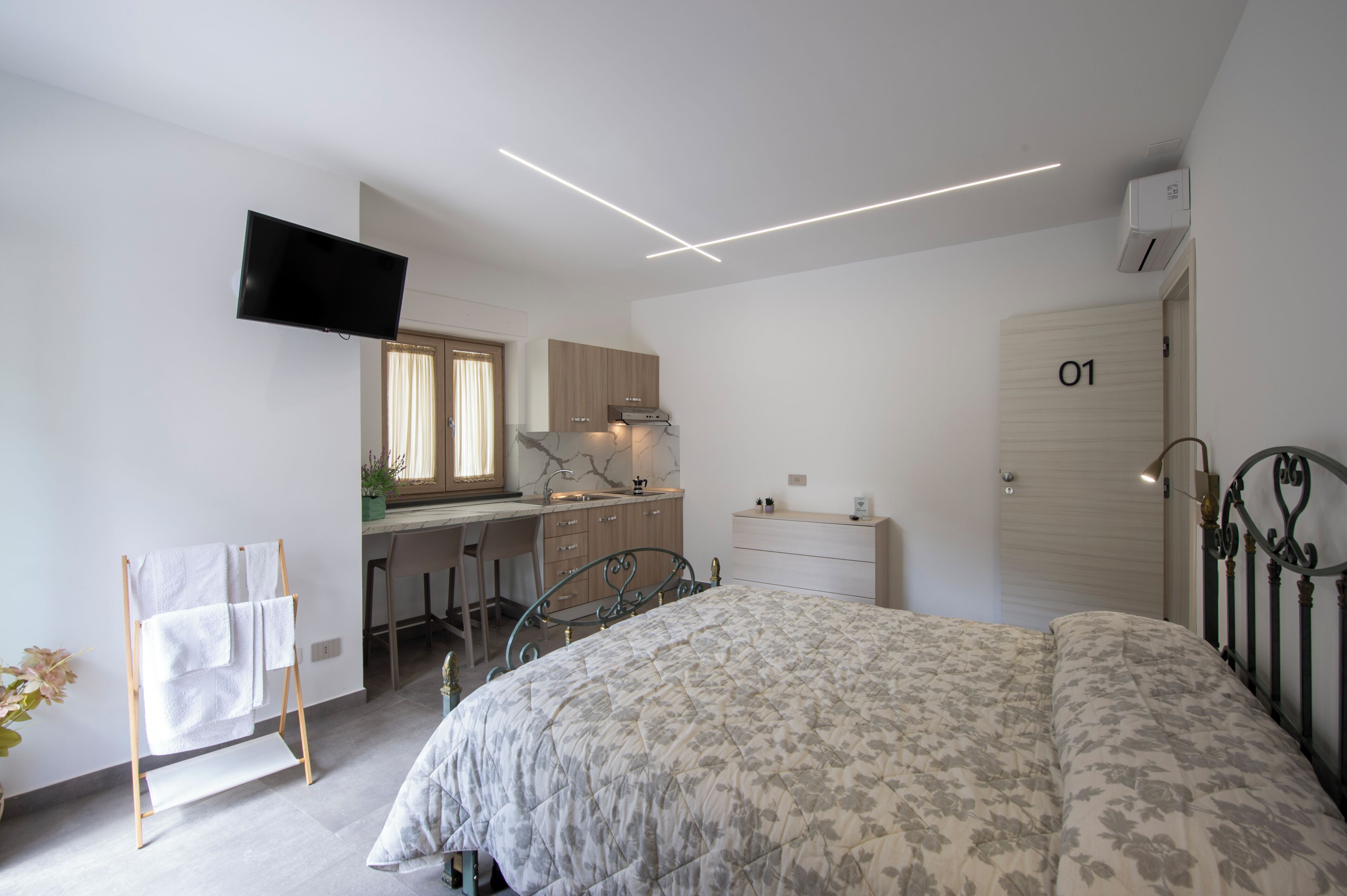 A bedroom with a bed, a desk, a chair, a TV, and a bathroom door.