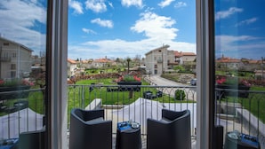 Een balkon met buitenmeubilair, uitzicht op een woonwijk en een heldere lucht.