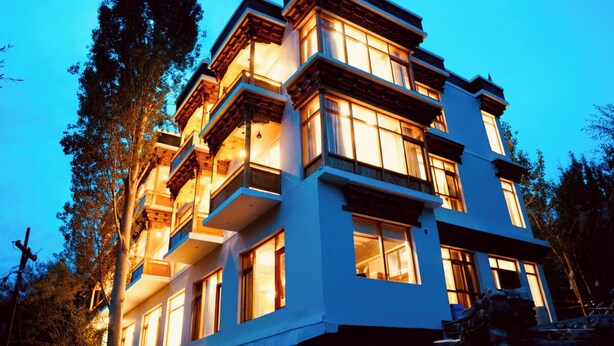 A multi-story building with balconies and large windows, surrounded by trees. - Hotel Walnut Ladakh (Leh)