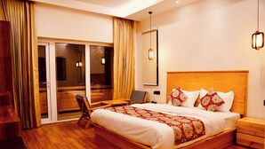 A hotel room with a wooden bed, a desk, a chair, a large window, and a sliding door. - Hotel Walnut Ladakh (Leh)