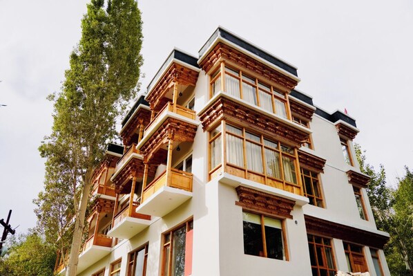 A multi-story building with balconies, large windows, and a traditional architectural style. - Hotel Walnut Ladakh (Leh)
