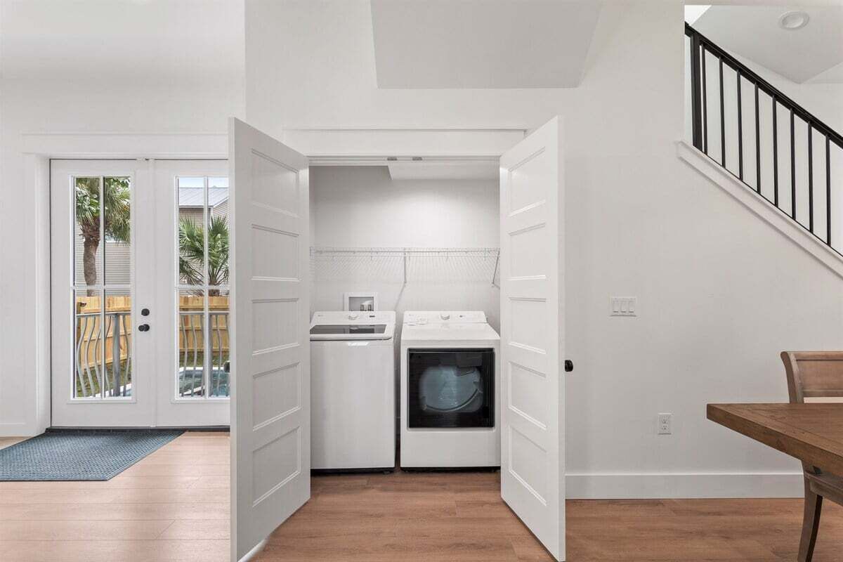 A laundry room with a washing machine, dryer, and a door leading to a balcony.