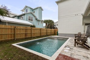 A rectangular swimming pool with a wooden fence and a brick patio area. - New Destin Beach Home | Pool | Walk to Beach! (Destin)