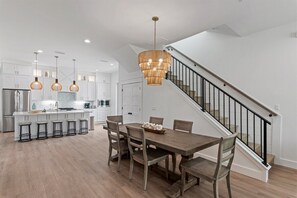 A modern kitchen with a central island, bar stools, and pendant lighting. - New Destin Beach Home | Pool | Walk to Beach! (Destin)