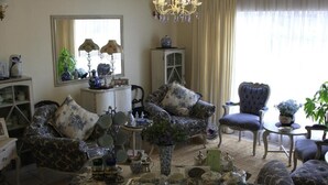 A traditional living room with patterned furniture, a chandelier, and a tea set on a tray. - THE SUMMER PLACE BOUTIQUE GUESTHOUSE (Bloemfontein)