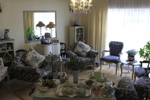 Un salón tradicional con muebles estampados, una araña y un juego de té sobre una bandeja.