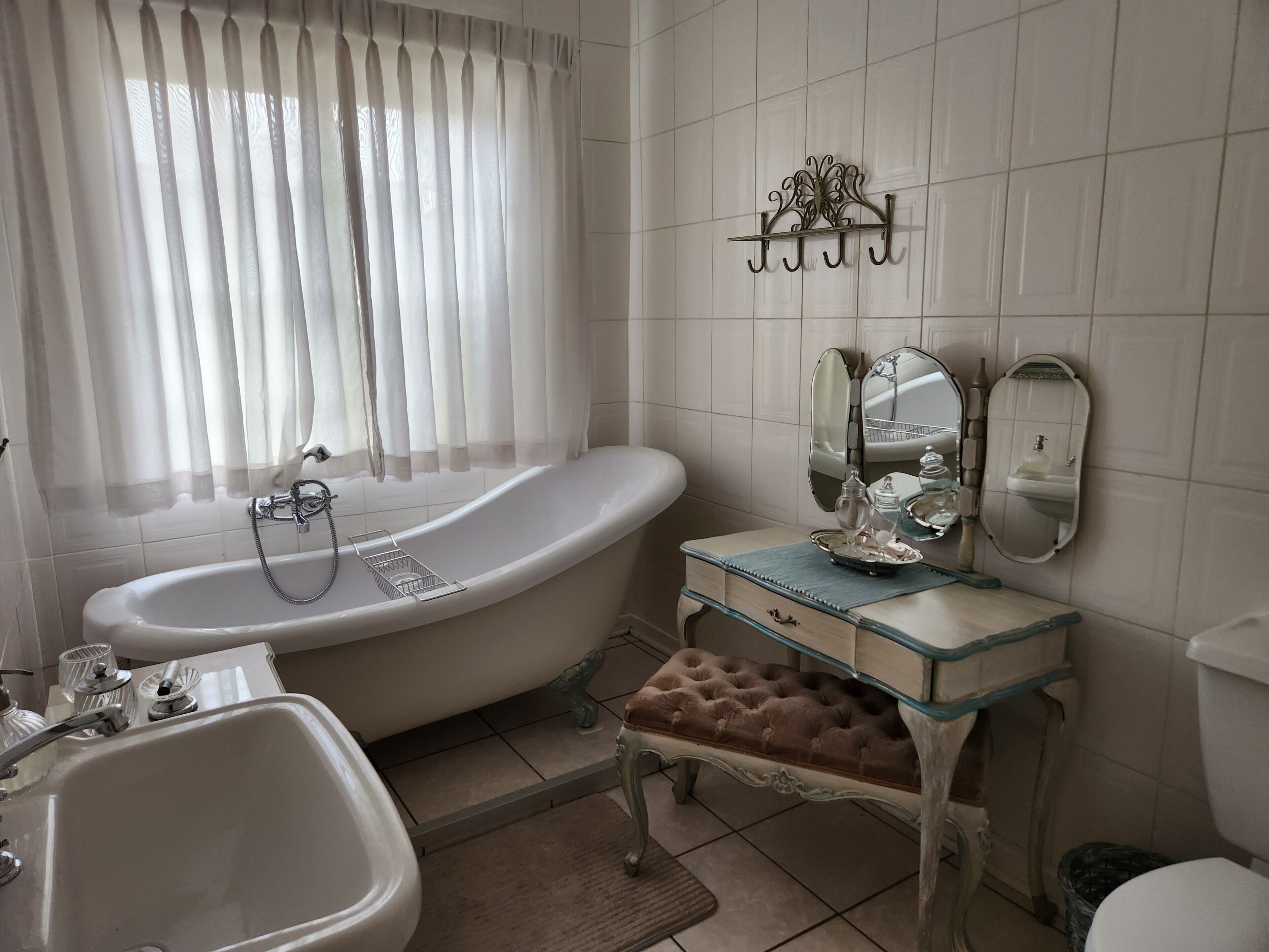 Un baño con bañera, lavamanos, tocador con espejo e inodoro.