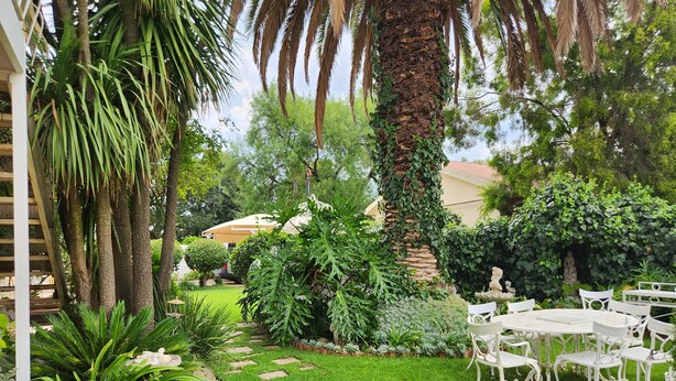 A well-maintained garden with a patio area featuring white outdoor furniture. - THE SUMMER PLACE BOUTIQUE GUESTHOUSE (Bloemfontein)