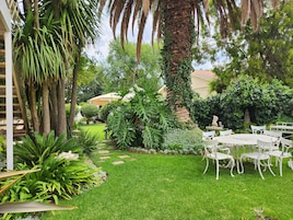 Un jardín bien cuidado con un patio amoblado con mobiliario exterior blanco.