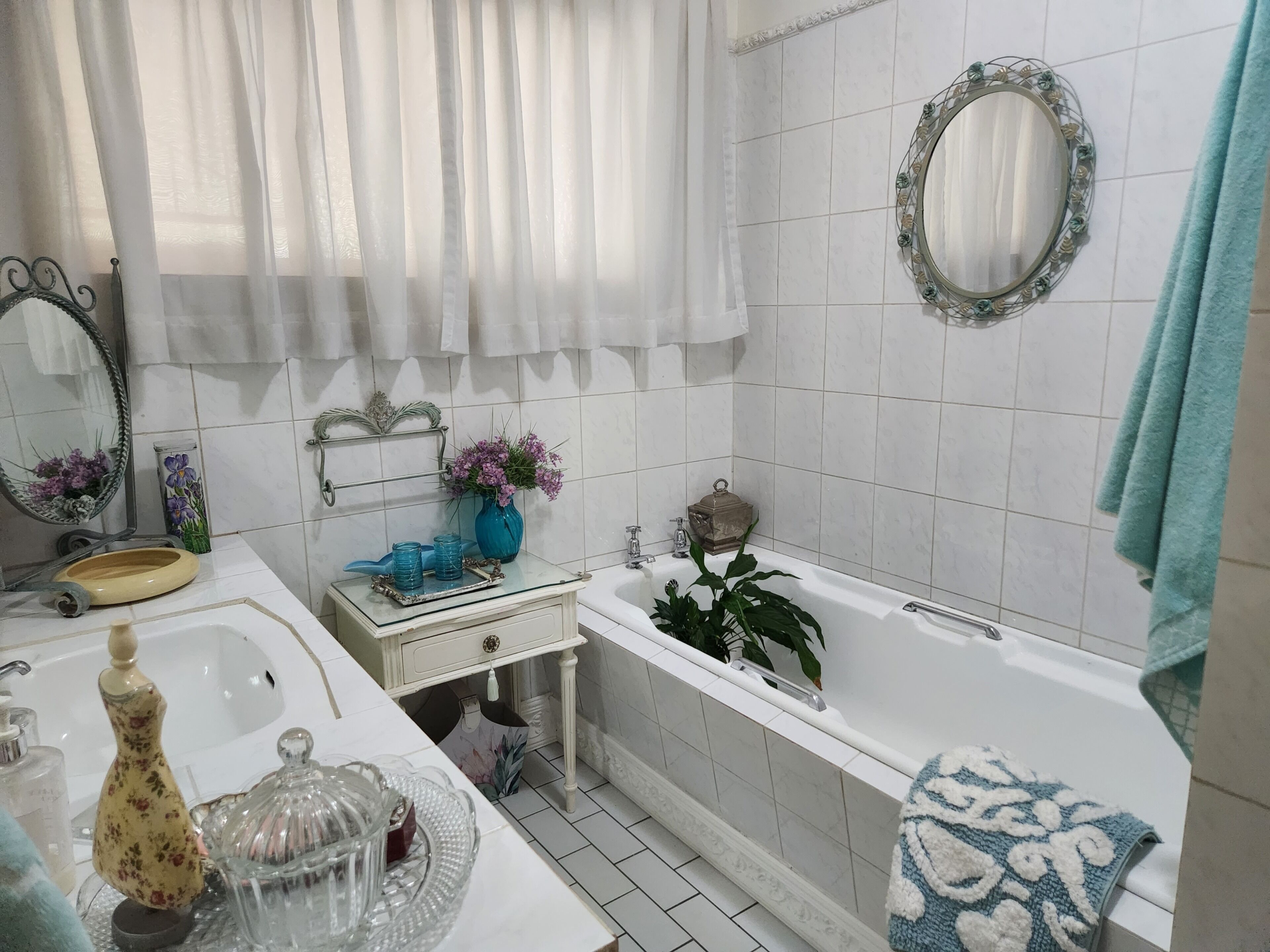 A bathroom with a sink, mirror, vanity, bathtub, and towel rack.