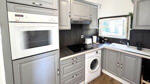 A kitchen with grey cabinets, a built-in oven, a washing machine, and a window with a view. - VIEUX NICE VISTA AP4503 by Riviera Holiday Homes (Niza)