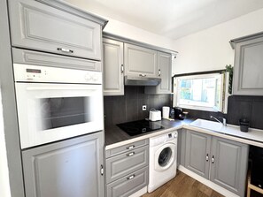 A kitchen with grey cabinets, a built-in oven, a washing machine, and a window with a view. - VIEUX NICE VISTA AP4503 by Riviera Holiday Homes (Niza)