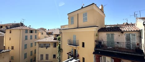 A residential area with buildings featuring terracotta roofs and balconies, under a clear sky.