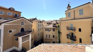 A narrow street with buildings featuring balconies and a clock tower. - VIEUX NICE VISTA AP4503 by Riviera Holiday Homes (Niza)