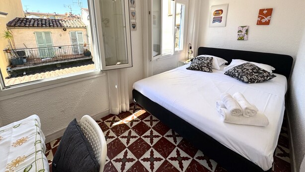 A hotel room with a bed, a chair, a window, and a view of the outside. - VIEUX NICE VISTA AP4503 by Riviera Holiday Homes (Niza)