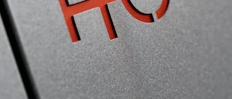Primer plano de una superficie metálica con el logotipo rojo 'HC'.