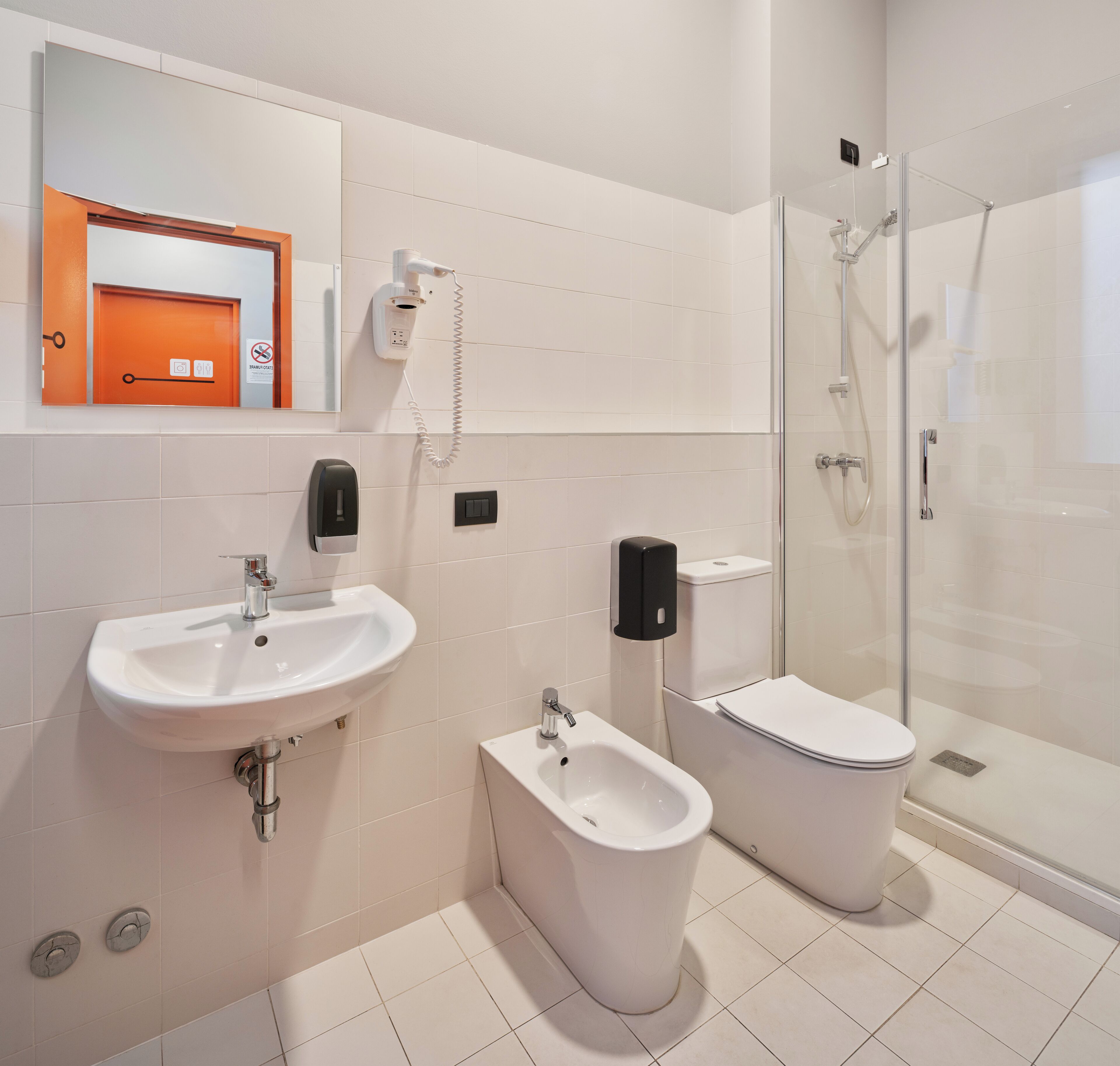 A modern bathroom with a sink, bidet, toilet, and glass shower enclosure.