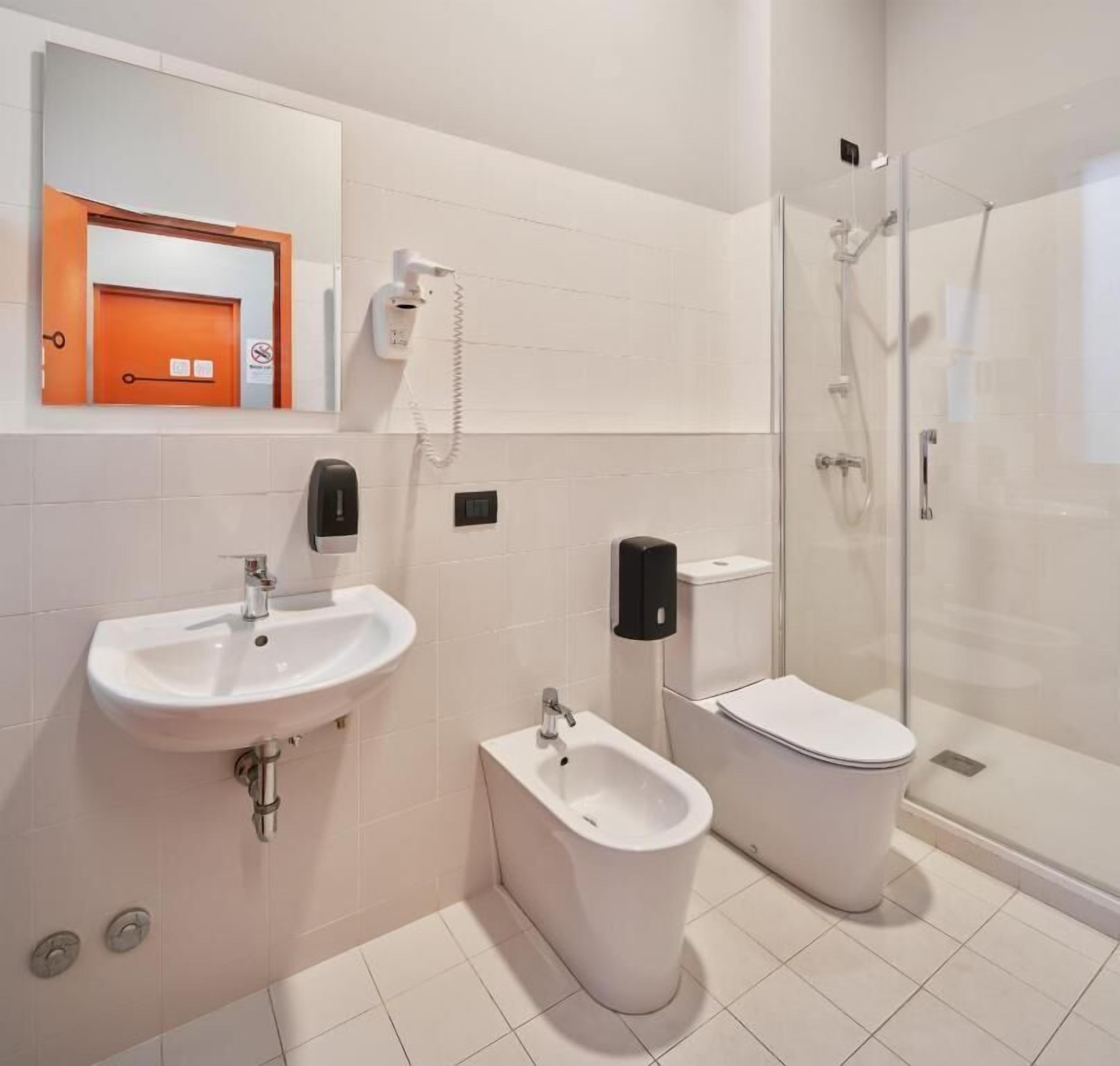 A modern bathroom with a sink, bidet, toilet, and shower.
