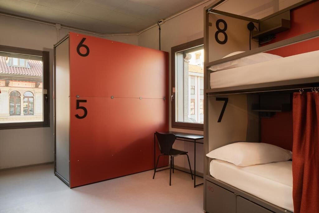A dormitory room with bunk beds, a desk, and a chair.