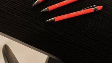 Cuatro bolígrafos rojos con adornos plateados sobre una superficie negra.