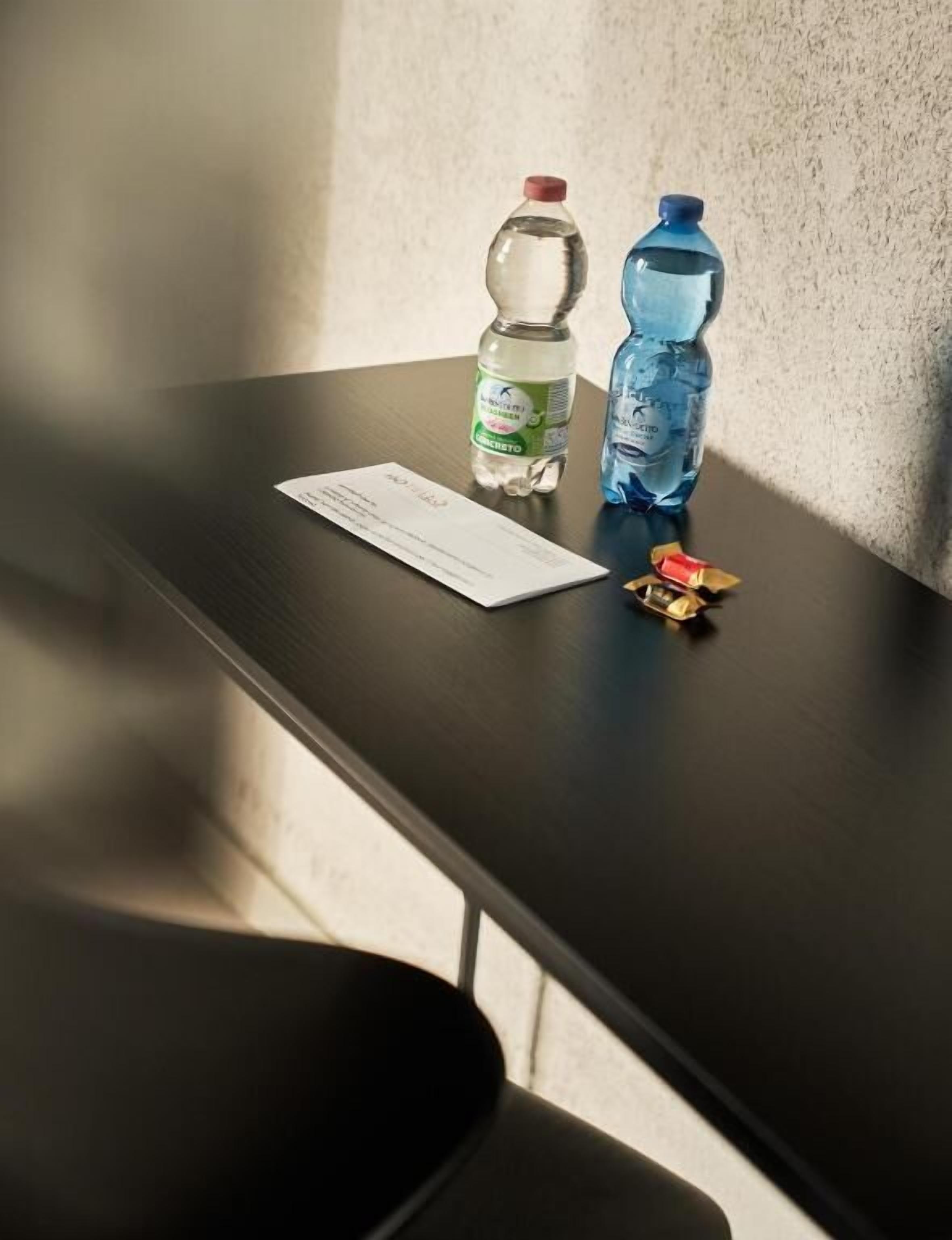 A table with two water bottles, a receipt, and a small packet on a dark surface.