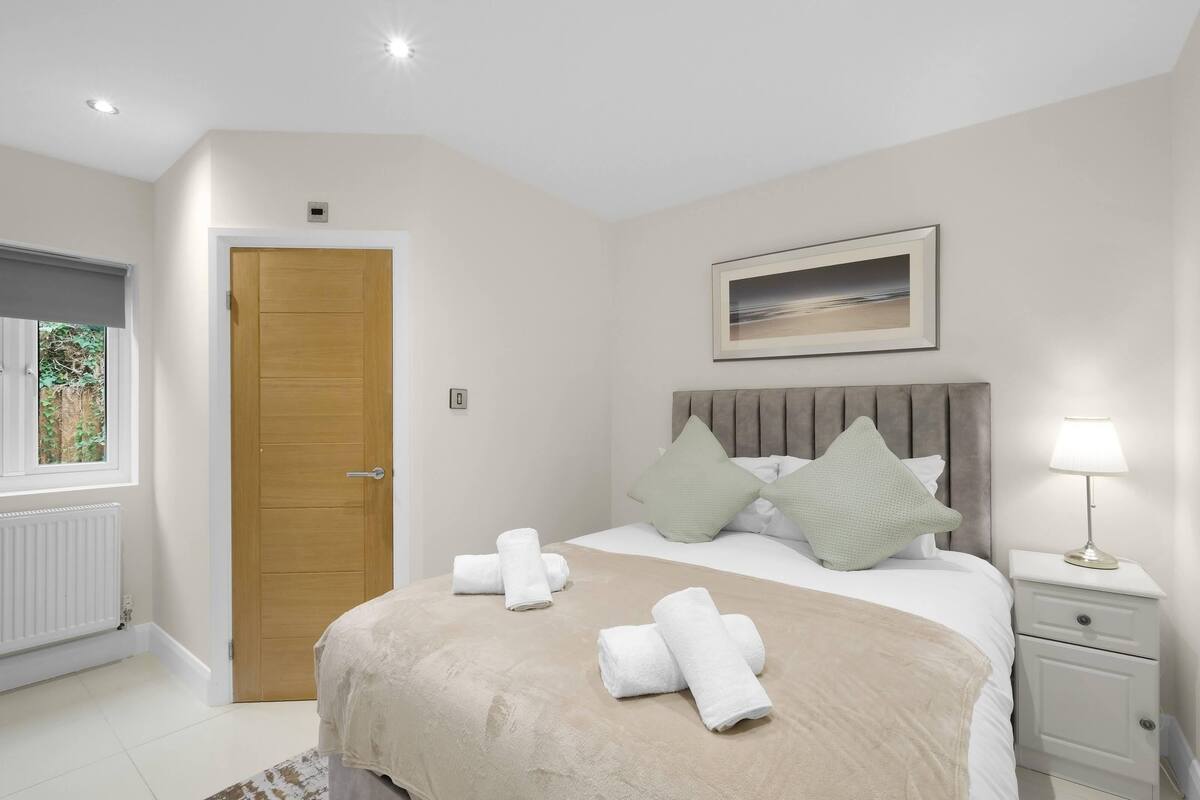 Een hotelkamer met een bed, nachtkastje, raam en deur.