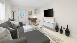 Ein modernes Wohnzimmer mit einer Couch, einem Couchtisch und einem an der Wand befestigten Flachbildfernseher.
