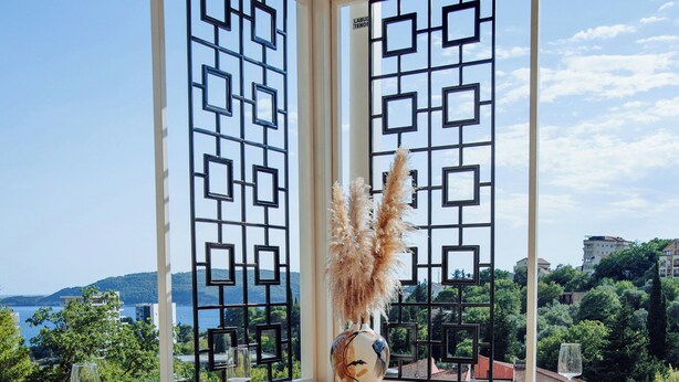 A dining area with a view of the sea, a decorative partition, and modern furniture. - Ststus M apartments 102 (Becici)