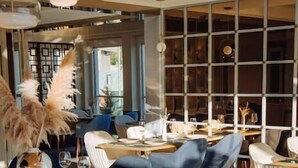 A restaurant interior with round tables, blue chairs, and a modern design. - Ststus M apartments 102 (Becici)