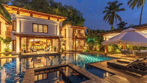 A modern resort with a large swimming pool, outdoor seating, and a well-lit patio area. - Azara is a serene luxury sanctuary in Goa designed for calm and escape. (Candolim)