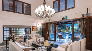A spacious living area with a large sofa, a coffee table, and a chandelier. - Azara is a serene luxury sanctuary in Goa designed for calm and escape. (Candolim)