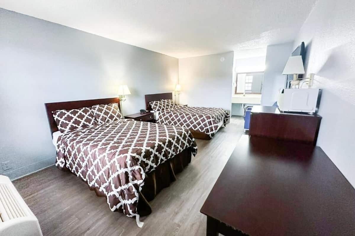 A hotel room with two beds, a desk, and a chair.