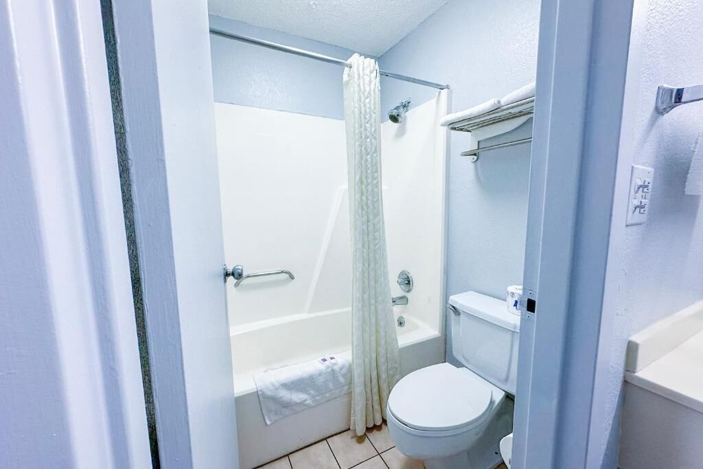 Un baño con bañera, inodoro y cortina de ducha.