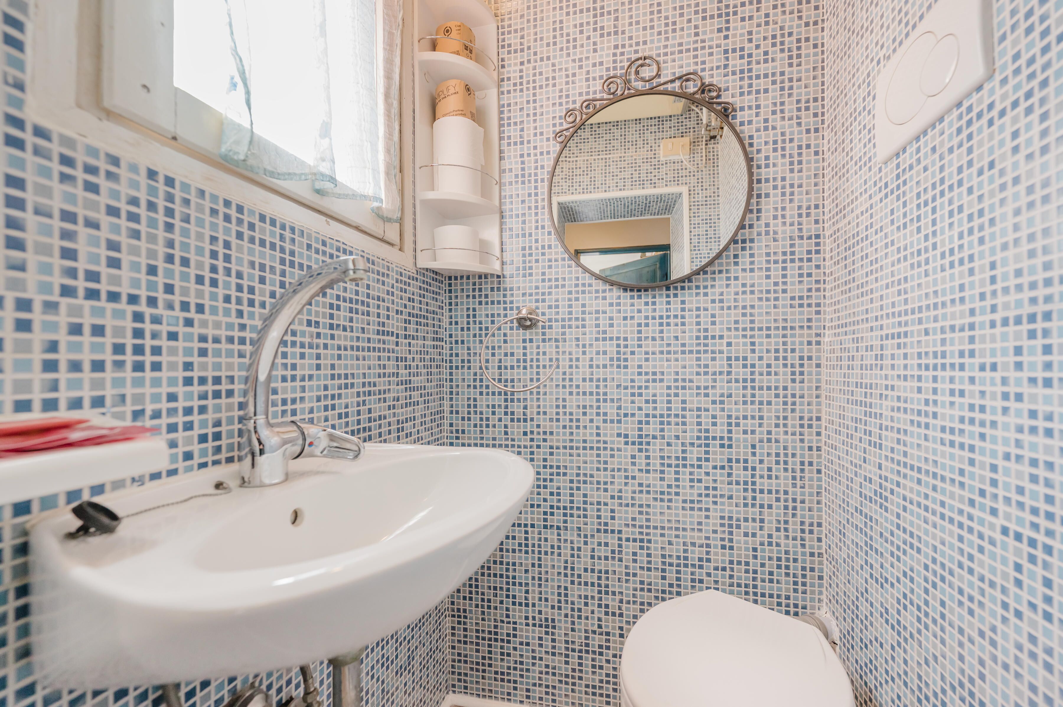 Une salle de bain avec un lavabo blanc, des toilettes et un miroir au mur.