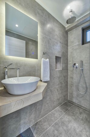 Ein modernes Badezimmer mit einem großen, ovalen Waschbecken, einer Handbrause und einem kleinen Fenster.