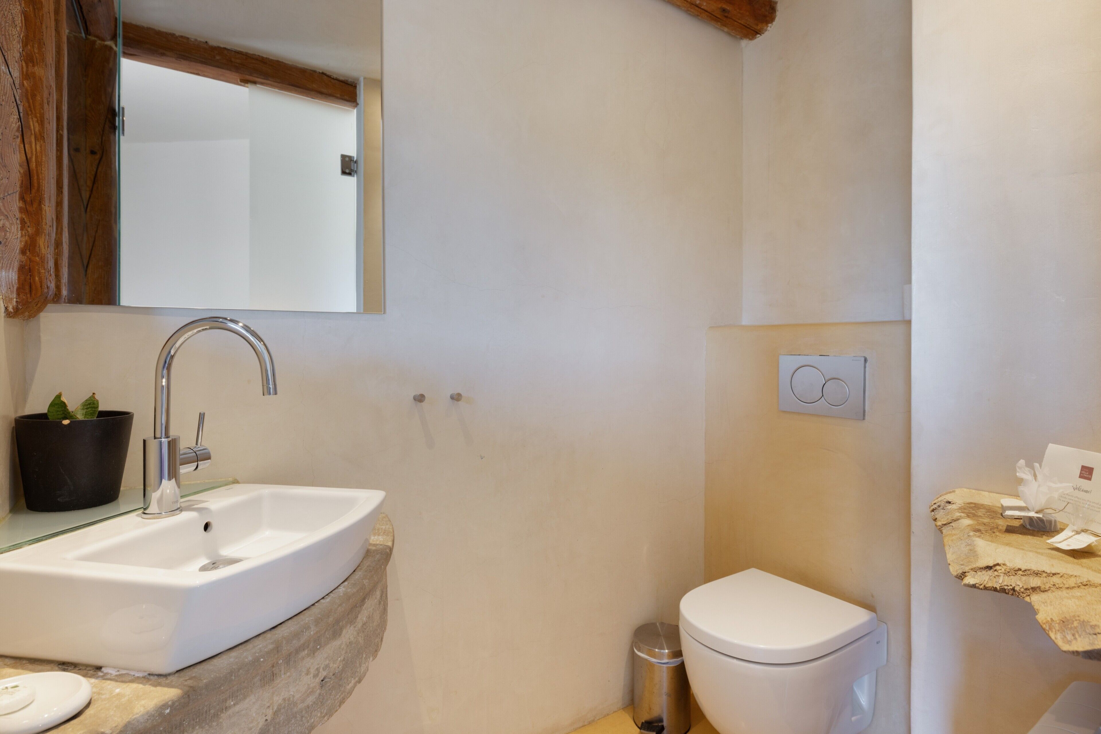 A bathroom with a white sink, a mirror, a toilet, and a trash can.