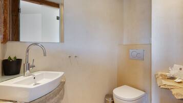 A bathroom with a white sink, a mirror, a toilet, and a trash can.