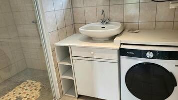 Ein kleines Badezimmer mit Waschbecken, Waschmaschine und einem kleinen Spiegel.